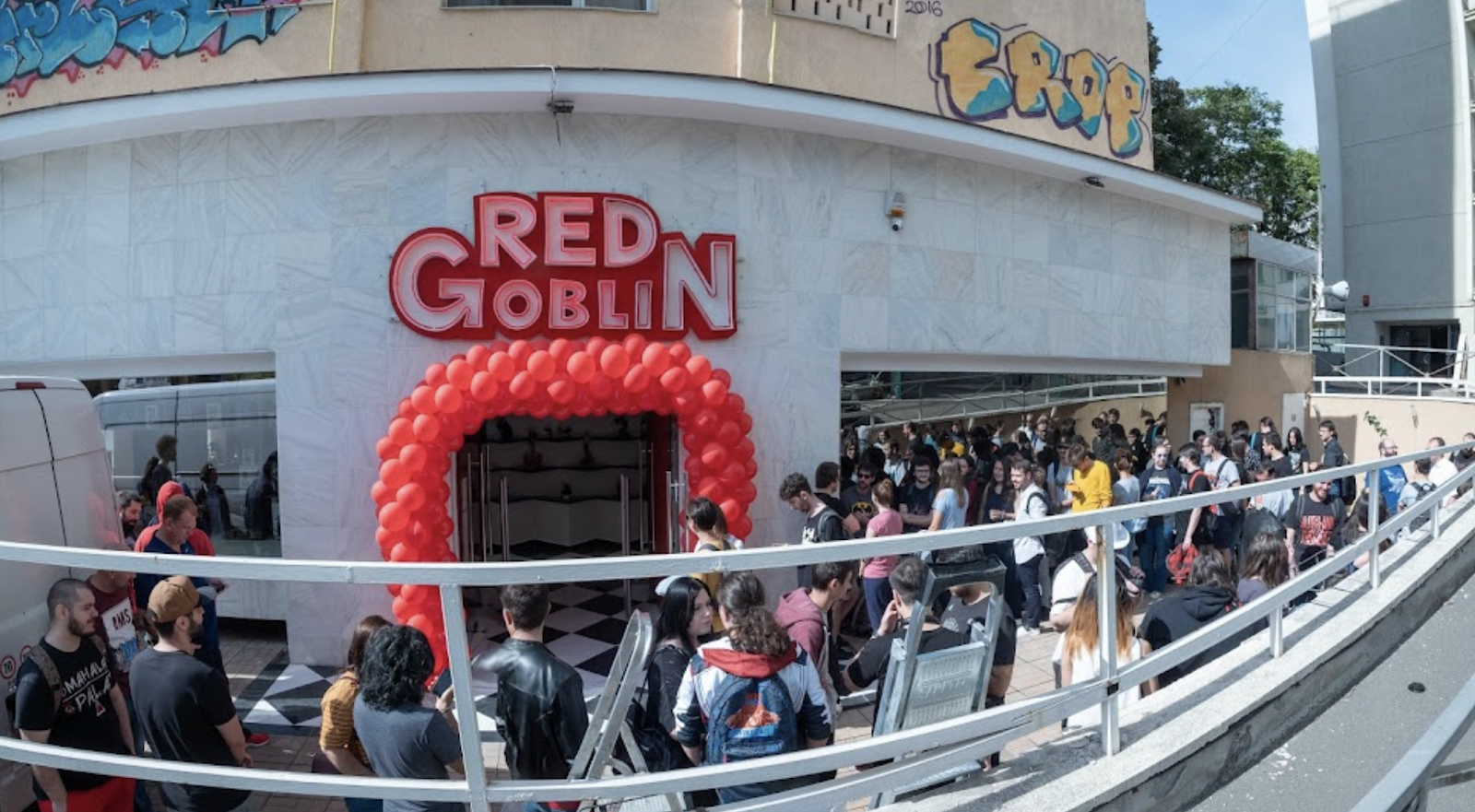 The Red Goblin storefront in Bucharest, crowd gathered under a red balloon arch on opening day